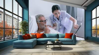 senior man with smiling nurse, takes care and discussion the result in chart board and cheer on bed at nursing home Wall mural