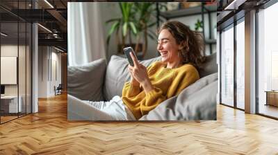 Young happy woman using mobile cell phone sitting on couch at home. Smiling cheerful lady laughing holding smartphone having fun while buying in ecommerce shop or watching funny videos, Generative AI  Wall mural