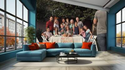 Cheerful family standing at table in garden and posing for photo. Wall mural