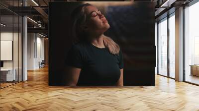 Exhausted woman touching hair in dark room Wall mural