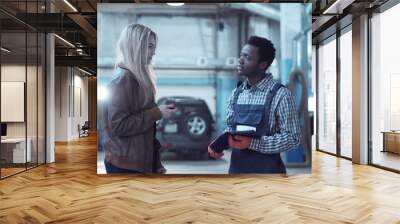 female blond client giving keys from her car to mechanic in uniform and talking about problem Wall mural