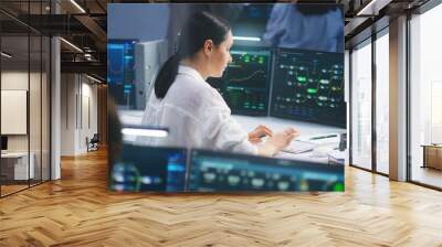 Female IT technical specialist works on computer with data server and blockchain network database in modern monitoring control room. Team of software engineers and big digital screens on background. Wall mural