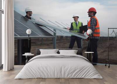 the engineer controls installation process of solar batteries, two employees in a uniform and in har Wall mural