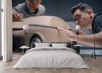 Two male automotive designers creating futuristic plasticine clay prototype of car with professional tools. Future design of new generation electric car. Working in modern car design studio. Wall mural