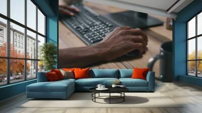 Unrecognizable African American man using computer keyboard and mouse while working on remote project Wall mural