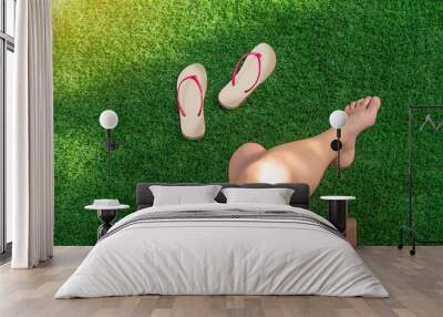 Selective focus of a girl sitting in a hammock on artificial turf with bare feet and flip-flops on the grass Wall mural