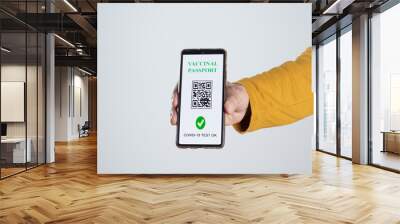 The digital vaccinal pass of the european union with the QR code on the screen of a mobile held by a hand with white background. Immunity from Covid-19. Travel without restrictions. Wall mural