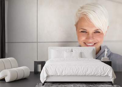 Casual portrait of blonde woman standing next to a wall Wall mural