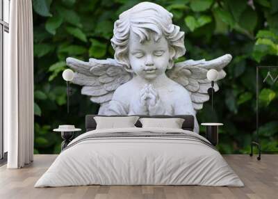 A white sandstone sculpture of a praying angel. Wall mural