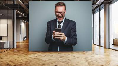 Weißer Geschäftsmann mit Brille freut sich über etwas auf seinem Telefon Wall mural