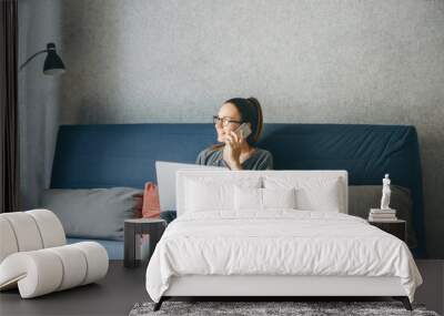 A girl works from home or a student is studying from home or a freelancer. She uses a laptop and a phone. Wall mural