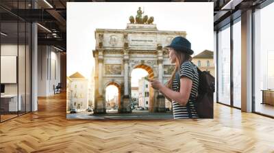 a tourist girl with a backpack looks sights in munich in germany. passes by the triumphal arch. Wall mural