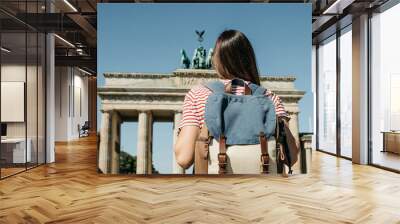 A tourist or a student with a backpack near the Brandenburg Gate in Berlin in Germany, looks at the sights. Wall mural