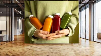 The woman is holding bottles of freshly squeezed juice in her hands. The concept of a healthy lifestyle, diet or detox, body care. Wall mural