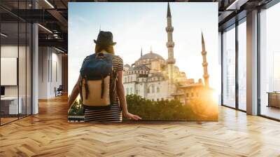 Young beautiful girl traveler in a hat with a backpack looking at a blue mosque - a famous tourist attraction of Istanbul. Travel, tourism, sightseeing. Wall mural