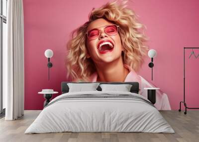 Blonde young and happy woman laughing, wearing 80s fashionable stylish clothes. Posing as a supermodel on a pink studio background Wall mural