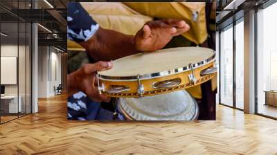 Hands and instrument of musician playing tambourine in the streets of Salvador in Bahia during a samba performance during carnival Wall mural