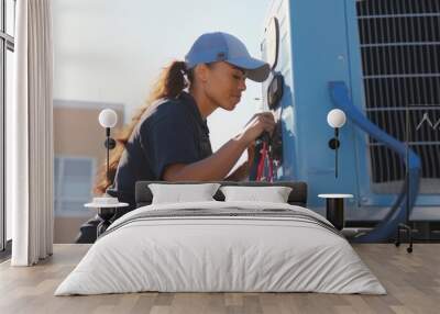 Young woman technician working on air conditioning outdoor unit. Female HVAC worker professional occupation  Wall mural