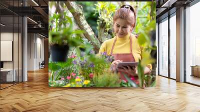 Asian woman receipt order customer and sale plant flower online on laptop in garden. People hobby and freelance gardening indoor at home, nature garden background Wall mural