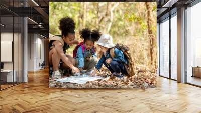 Group family children checking map for explore and find directions in the camping jungle nature and adventure. Tourism kids travel for destination and leisure trips for education and relax in nature  Wall mural