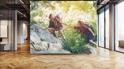 Group Hiker woman helping her friend climb up the last section of sunset in mountains. Traveler teamwork walking in outdoor lifestyle adventure and camping. Travel Concept. Wall mural