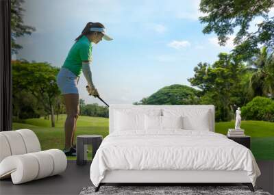 Healthy Sport. Asian Sporty woman golfer player doing golf swing tee off on the green , people presumably does exercise. Healthy Lifestyle Concept. Wall mural