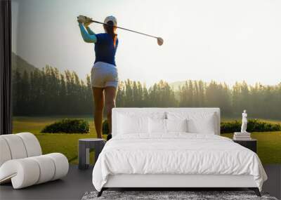 Healthy Sport. Asian Sporty woman golfer player doing golf swing tee off on the green evening time, she presumably does exercise.  Healthy Lifestyle Concept. Wall mural