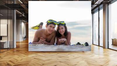 Summer Vacations. Beach travel couple having fun snorkeling. Asian smiling Couple lying  and enjoy on summer beach sand with snorkel equipment looking to side after swimming with fins. Wall mural