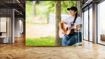 Woman people playing guitar in morning relax at nature garden home. Asia female beauty and smiling chill and enjoy in summer holiday.  Lifestyle Concept Wall mural