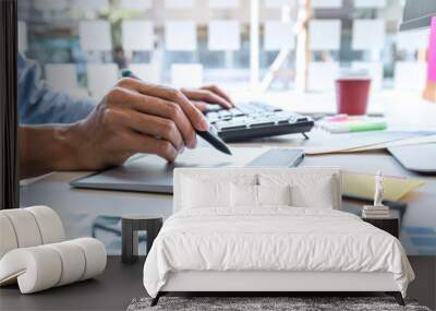 Image of male creative graphic designer working on color selection and drawing on graphics tablet at workplace with work tools and accessories in workspace Wall mural