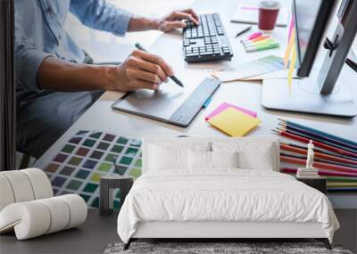 Image of male creative graphic designer working on color selection and drawing on graphics tablet at workplace with work tools and accessories in workspace Wall mural