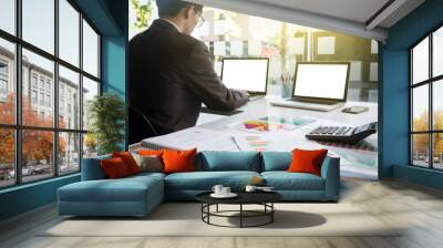 Image of young businessmen using laptop with many document graph at office in the morning Wall mural