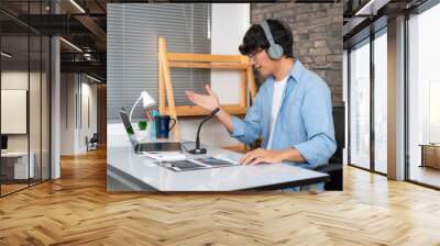 Male tutor wearing headset, using laptop and though camera to teaching new lesson by video conference on webcam Wall mural