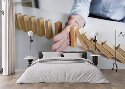 Risk and strategy in business, Close up of business woman hand stopping wooden block between three way from falling in the line of domino Wall mural