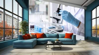 Scientist or medical in lab coat working in biotechnological laboratory, Microscope equipment for research with mixing reagents in glass flask in clinical laboratory Wall mural