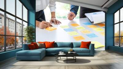 Two creative business people meeting and planning use post it notes sticky note on desk to share idea, Analysis data chart and graph with teamwork strategy brainstorming in office Wall mural