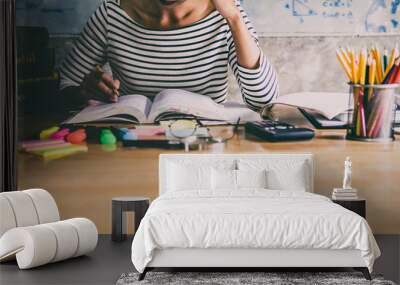 Young student sitting at desk in home studying and reading, doing homework and lesson practice preparing exam to entrance, education concept Wall mural