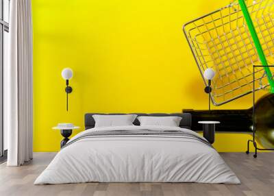 Bottle of wine and a shopping basket on a yellow background. Wall mural