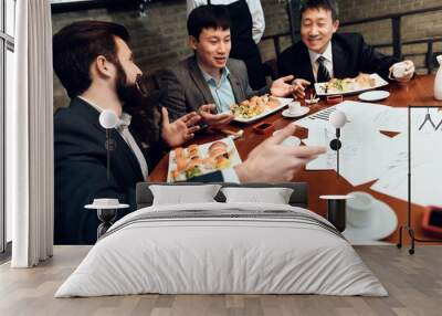 Meeting with japanese businessmen in restaurant. Men are eating sushi and talking. Wall mural