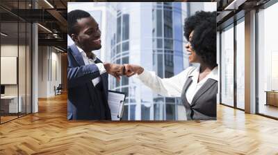 Businessman and businesswoman bumping their fist in front of corporate building Wall mural