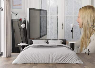 Attractive woman working at the computer and two monitors. Wall mural