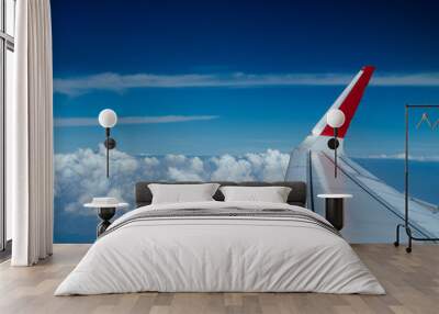 Wing of airplane flying over clouds Blue Sky  Wall mural