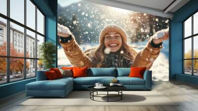 Smiling woman throwing snow in the air at sunny winter day Wall mural