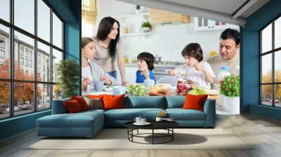 A place where family unites. Loving hispanic parents taking care of their little children while having lunch together at home Wall mural