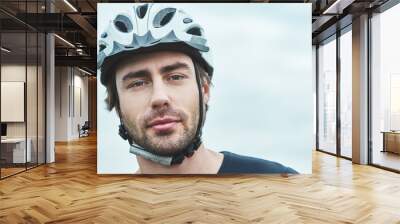 Attractive young man standing outdoors with protection helmet. Close up Wall mural