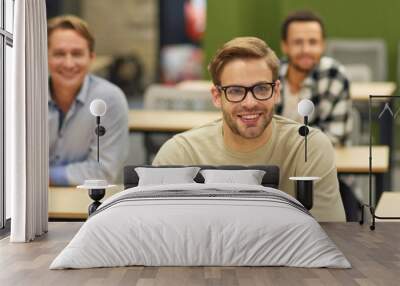 Business lecture. Group of happy multiracial people sitting in the modern office and listening to coach or speaker during seminar, selective focus on cheerful caucasian man Wall mural