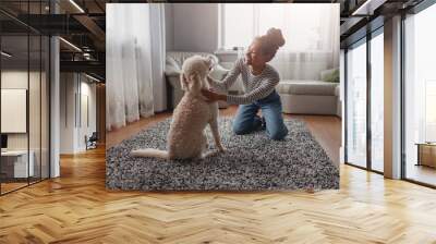 Cheerful happy young stylish woman laughing and playing with dog at home. Pet owner. Wall mural