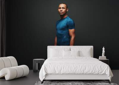 Choosing the right direction. Handsome african american sportsman standing over dark background Wall mural