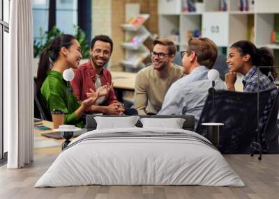 Creating success. Group of young happy multi racial business people communicating and sharing ideas while working together in the modern office Wall mural