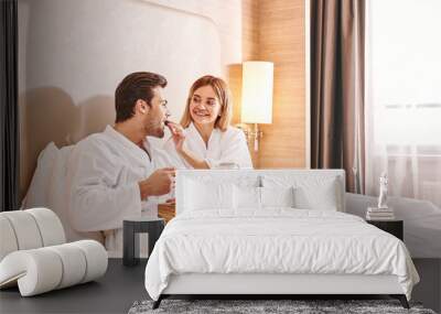 Feeding each other. Couple are eating in hotel room bed Wall mural